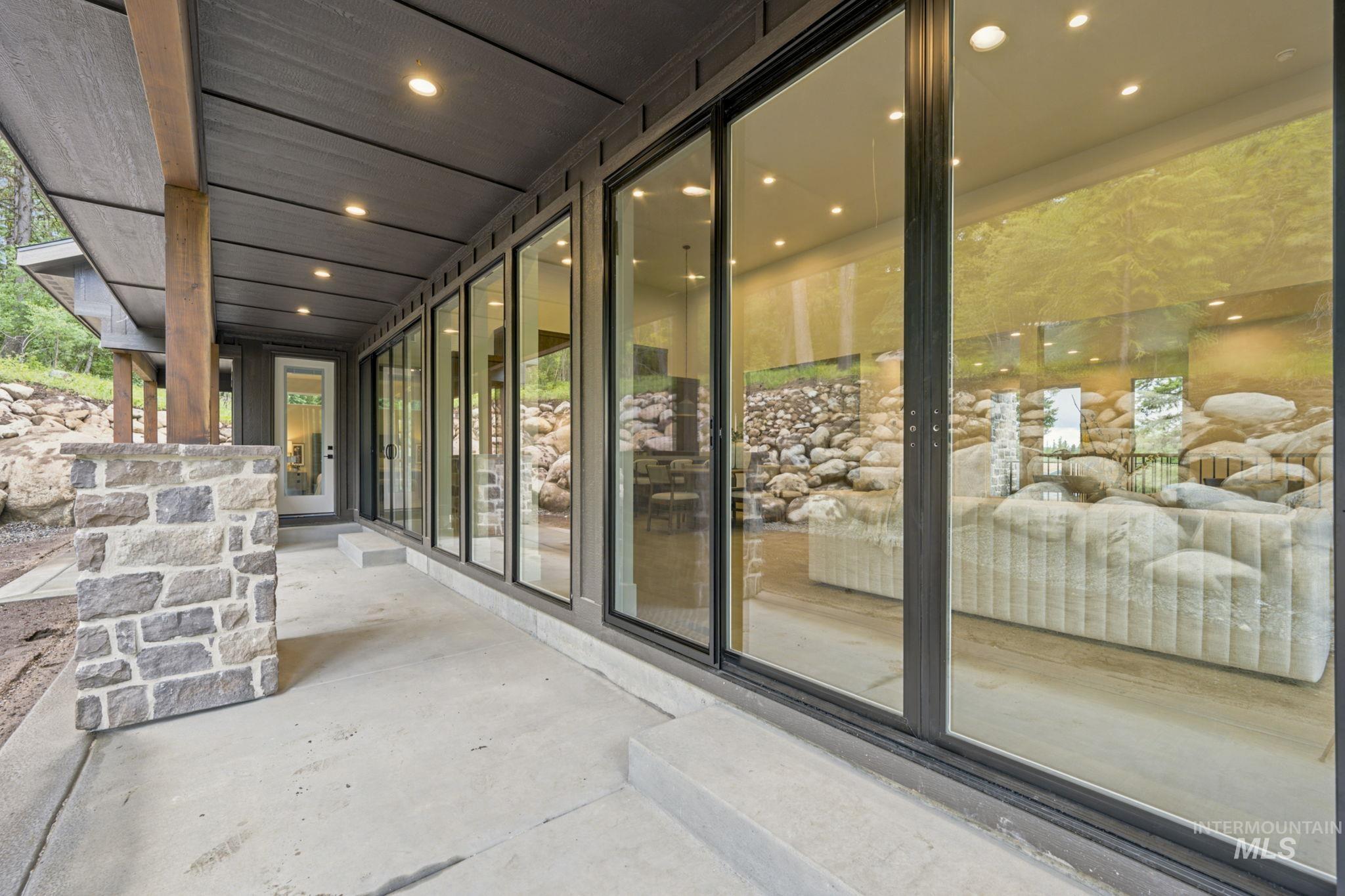Expansive concrete patio bordered by stacked stone landscaping - Off of Living to flat back yard