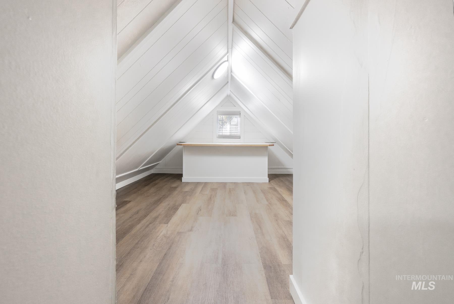 Additional living space featuring light wood finished floors and lofted ceiling