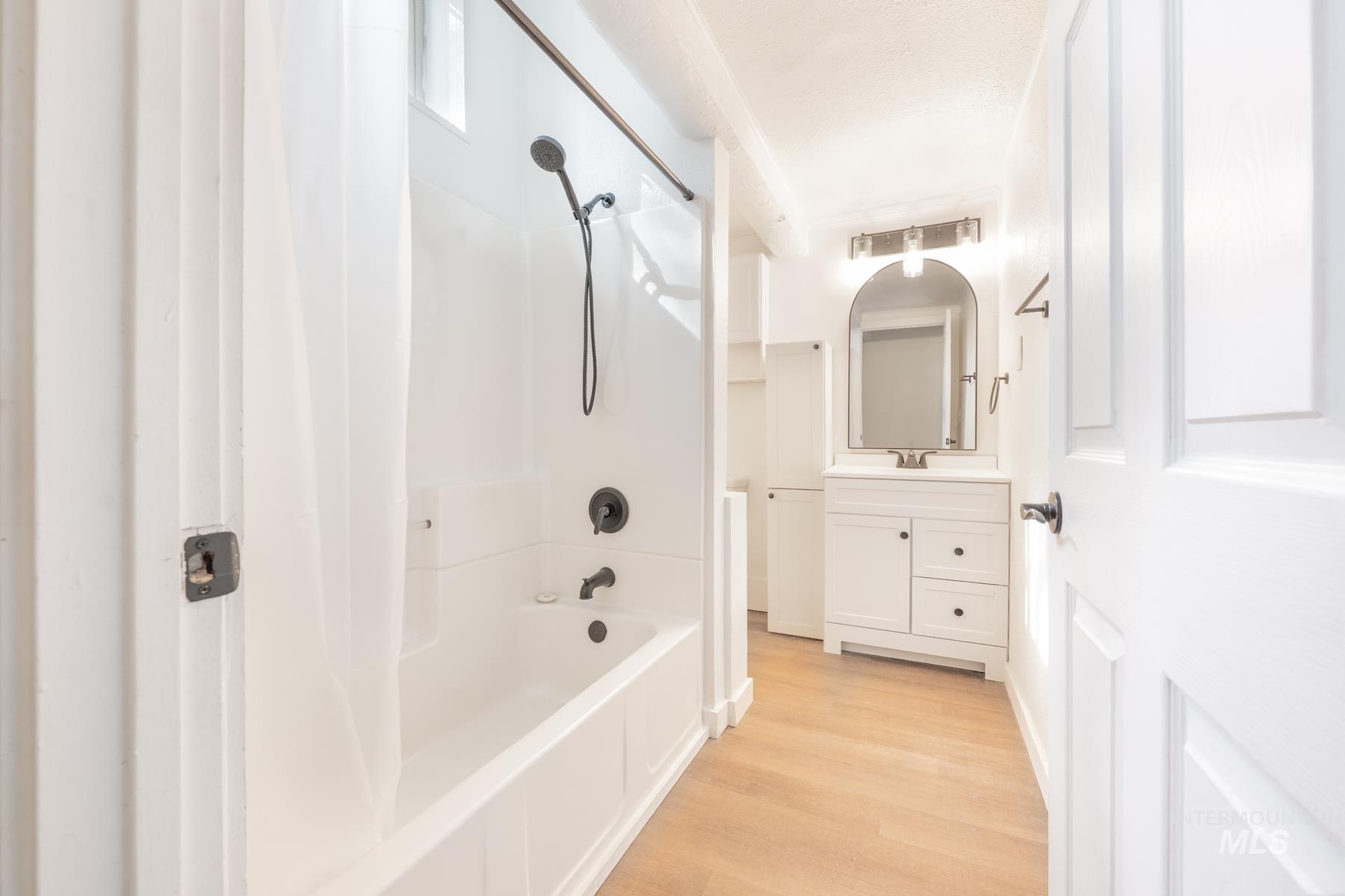 Bathroom with shower / bath combination with curtain, vanity, and light wood-style flooring