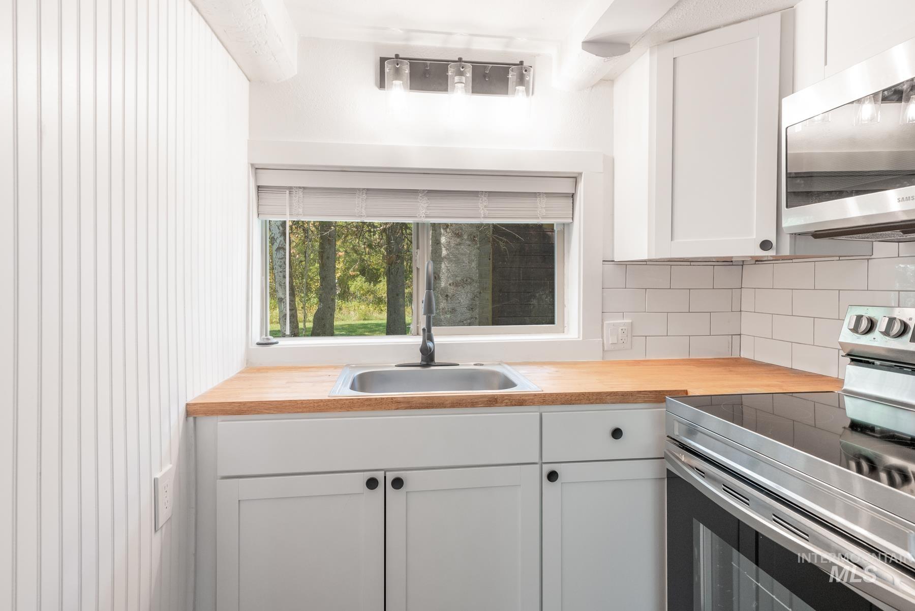 Kitchen featuring stainless steel appliances, white cabinets, and decorative backsplash