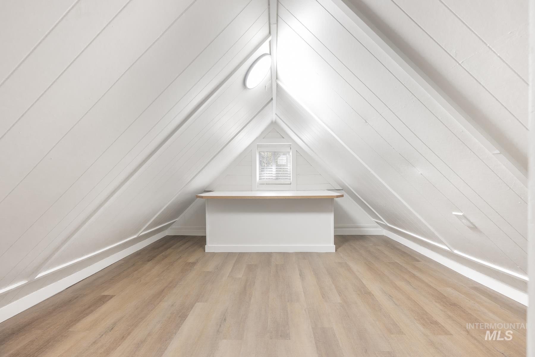Additional living space featuring light wood-type flooring and vaulted ceiling