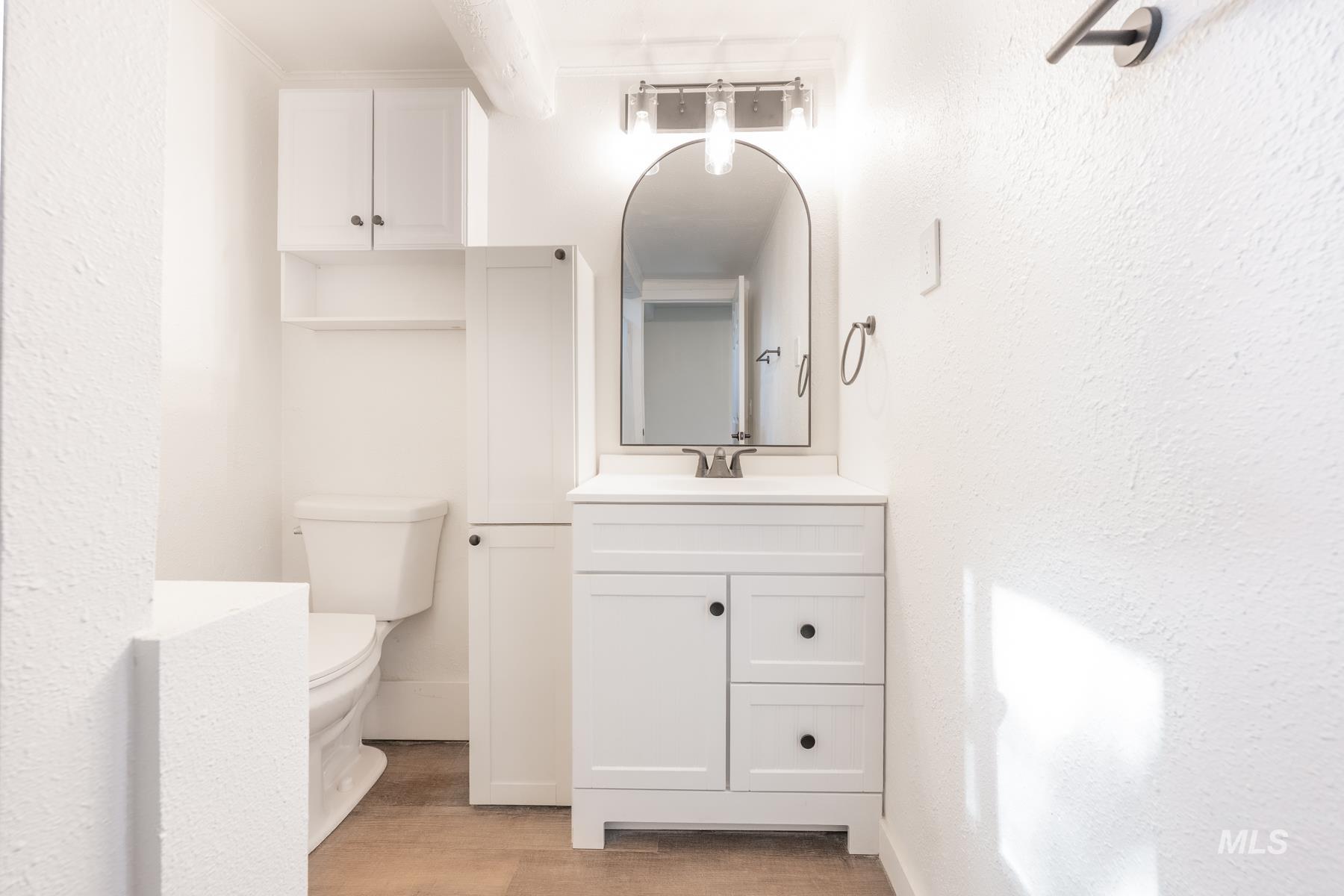 Bathroom with vanity, light wood-type flooring, and a textured wall
