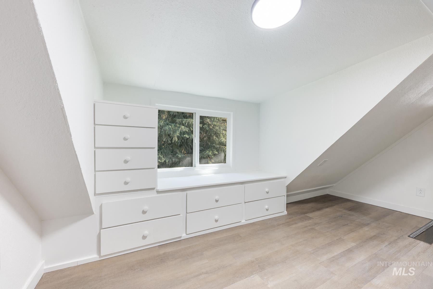 Additional living space with light wood-style flooring and baseboards
