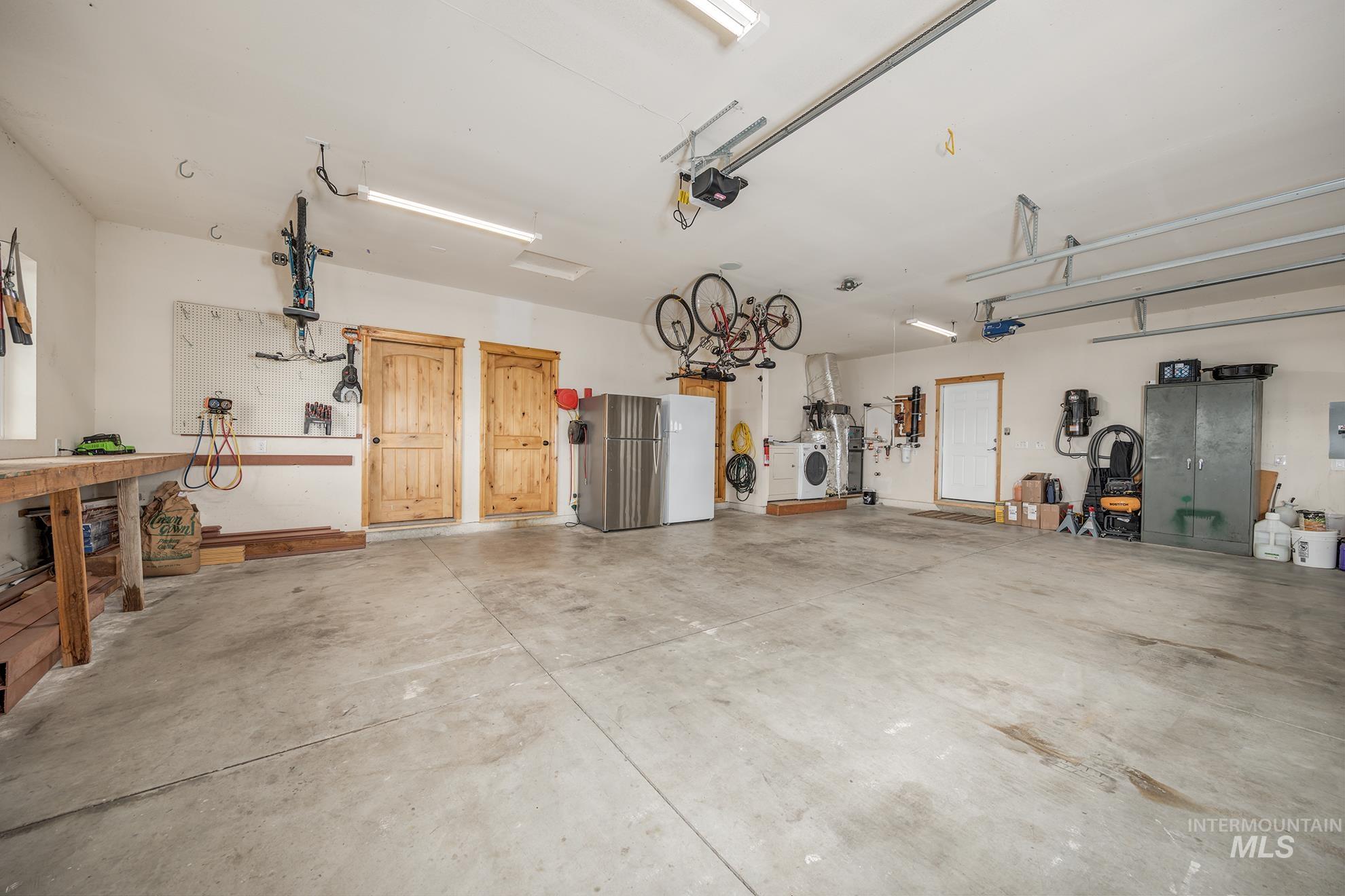 Garage with freestanding refrigerator, washer / clothes dryer, a workshop area, and a garage door opener