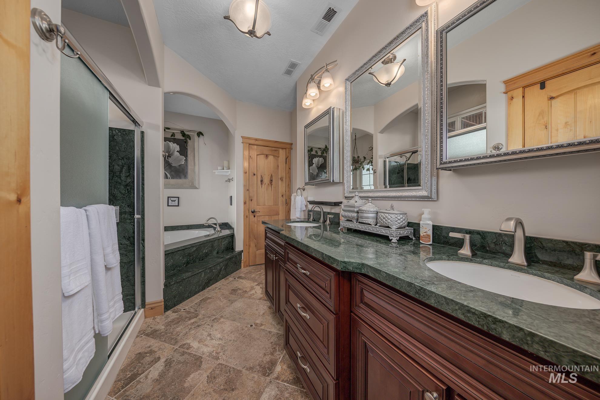 Master bathroom with a garden tub, double vanity, a walk-in shower, marble tub and shower surrounds, marble counter top and light stone finish flooring