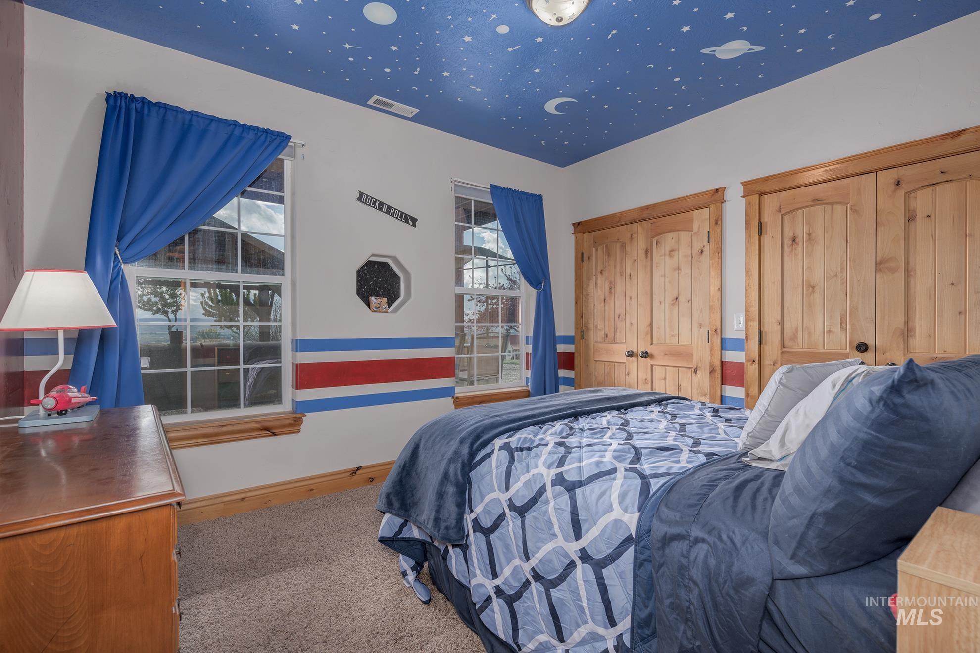 Bedroom with light colored carpet and multiple closets