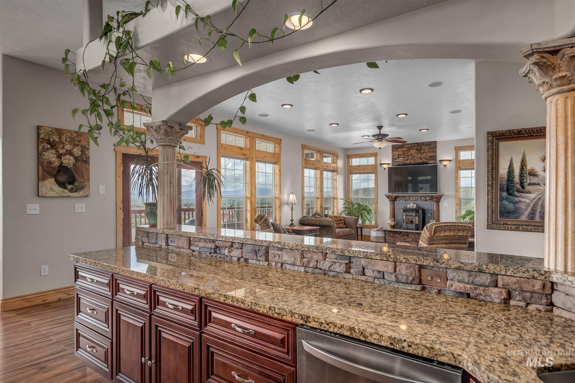 Kitchen with stainless steel dishwasher, light stone counters, a ceiling fan, open floor plan, and recessed lighting