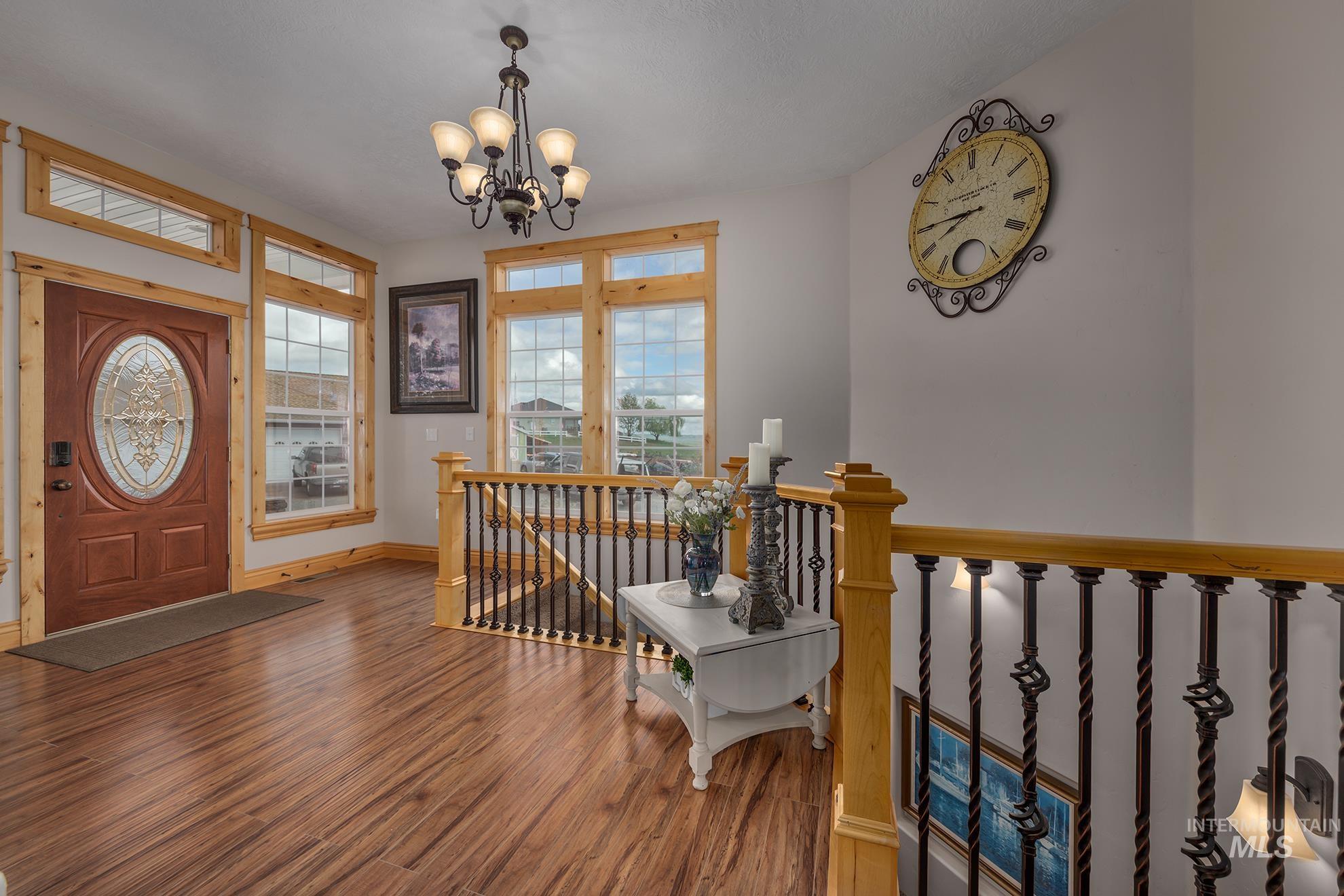 Entryway with wood finished floors and suspended lighting
