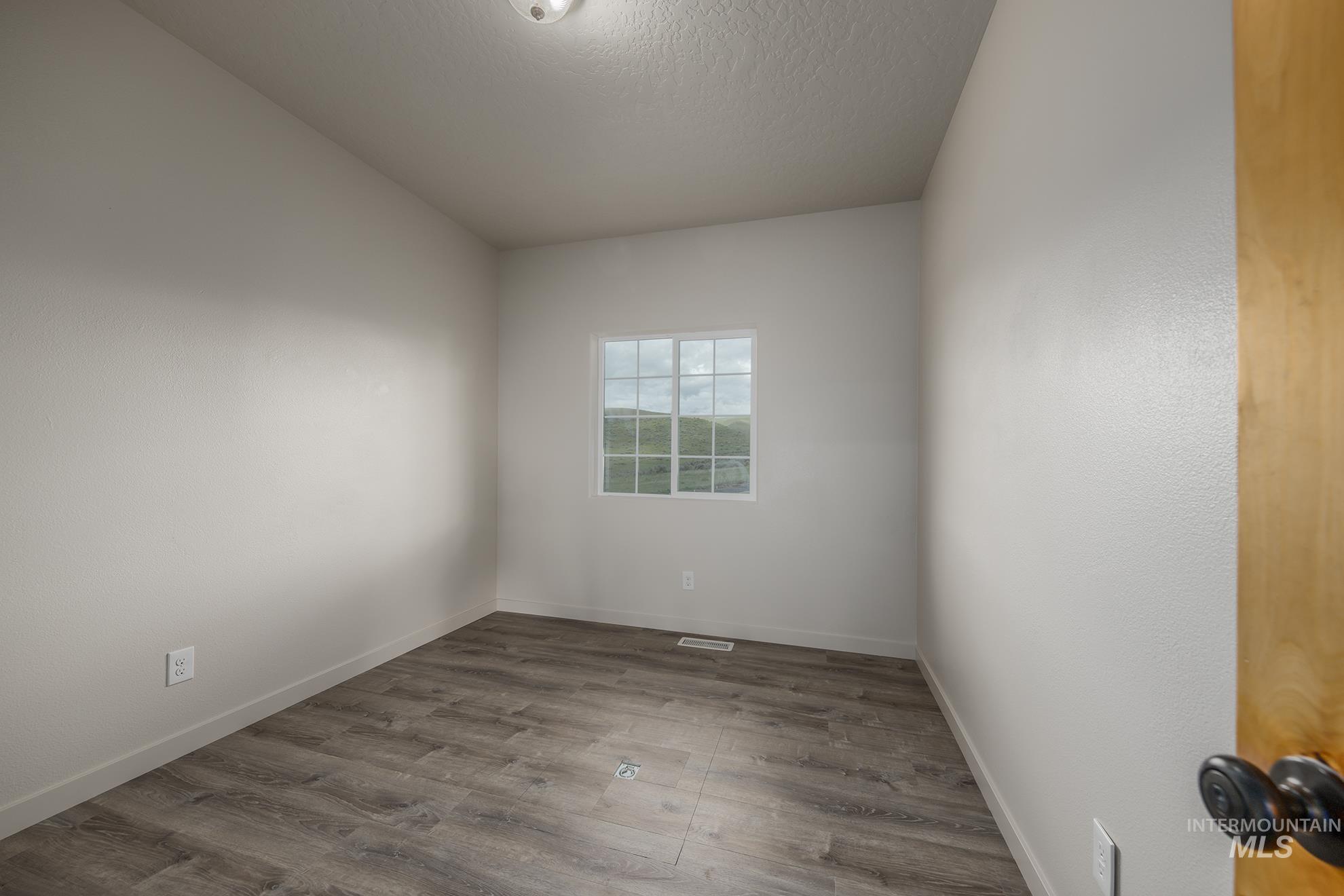 Spare room featuring wood finished floors and a textured ceiling - perfect office or art studio?