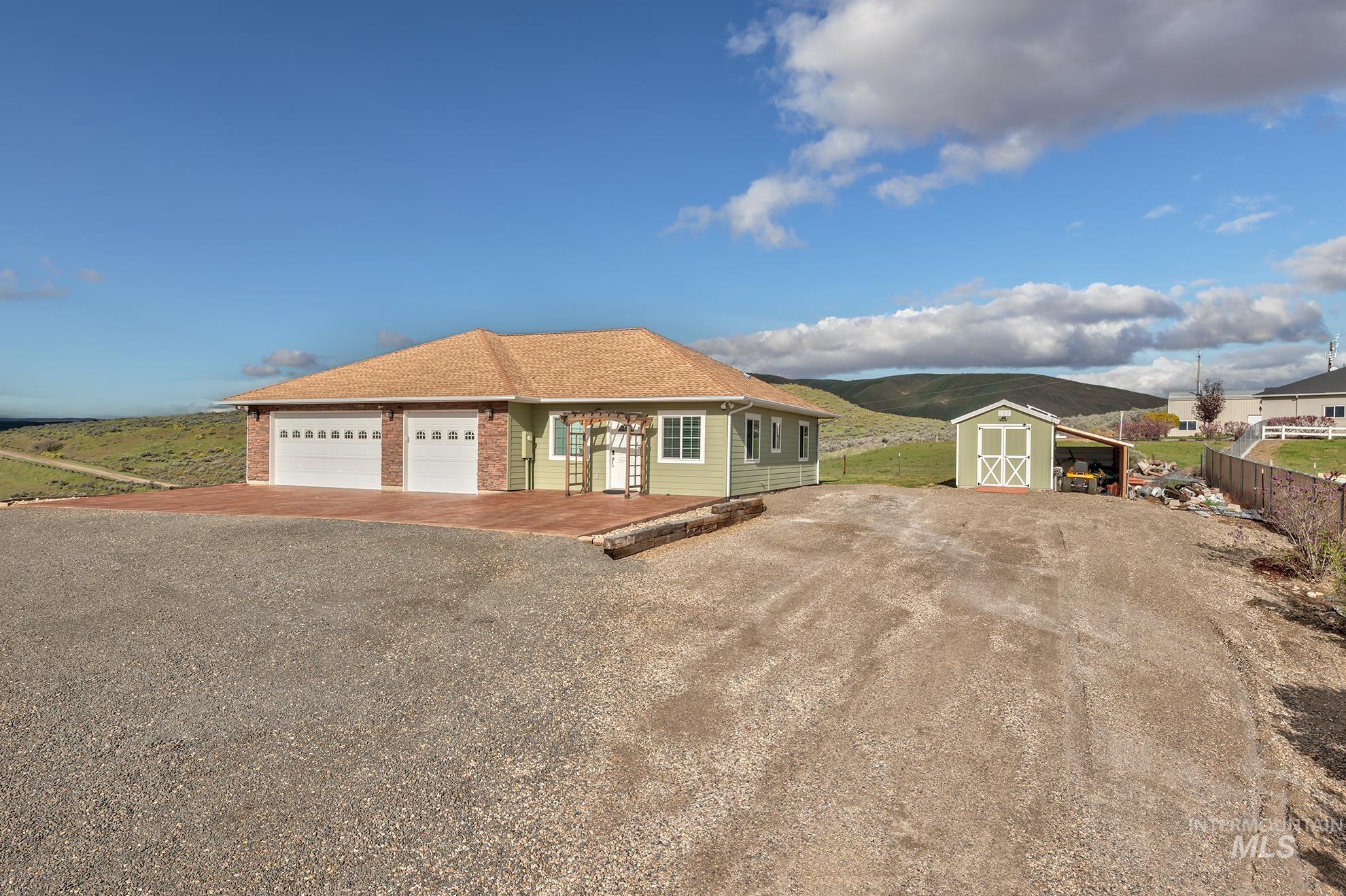 View of front of garage and apartment with driveway, a shingled roof, and a storage shed