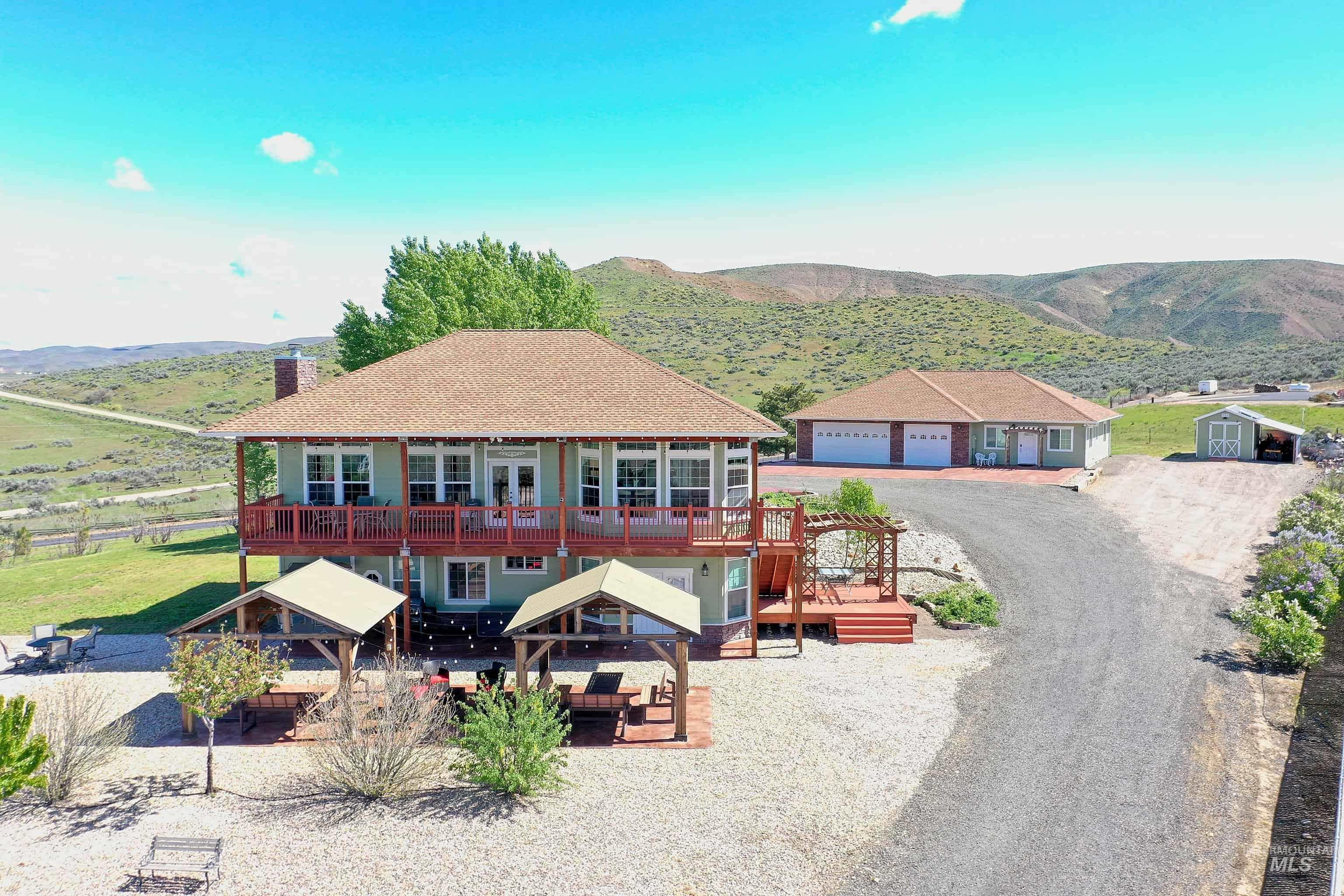 View of back of property with a deck with mountain view, a garage, a chimney, a patio area, and roof with shingles