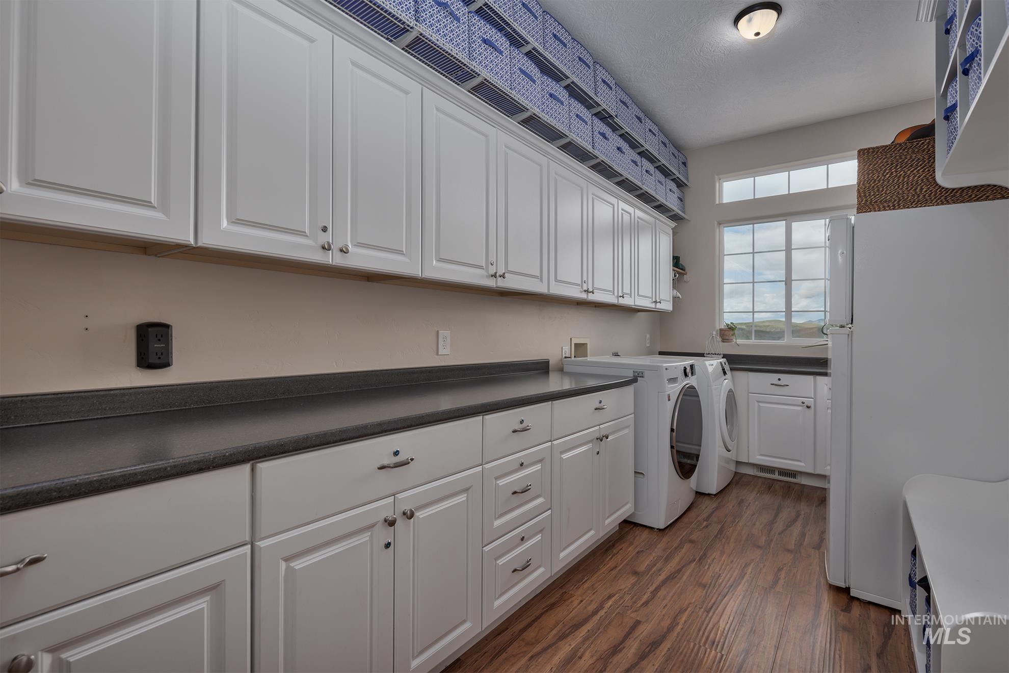 Laundry area featuring cabinet space, dark wood-style floors, and washer and clothes dryer