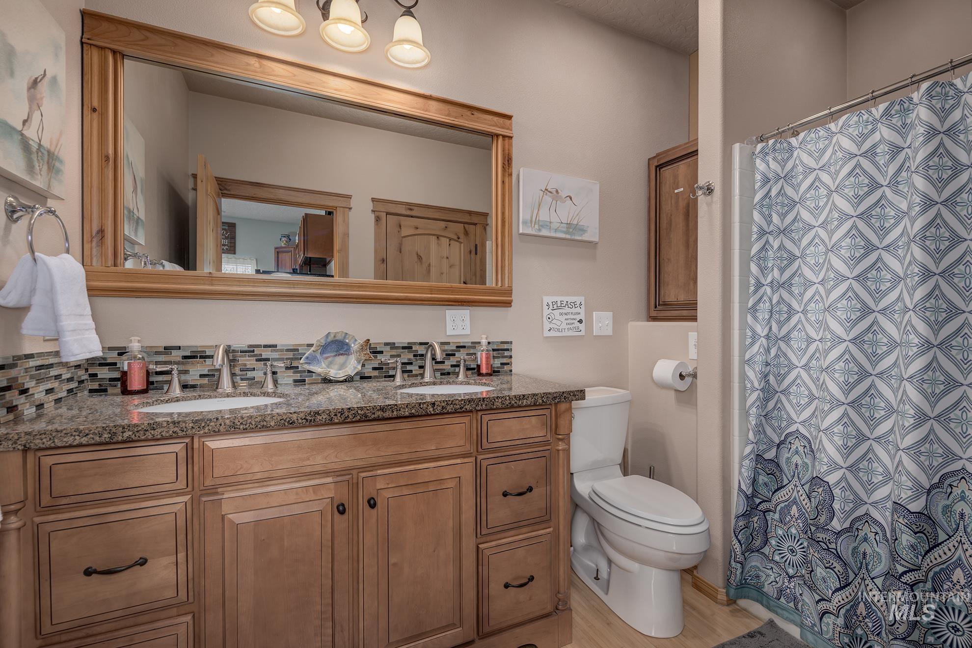 Guest house full bath with double vanity and a shower with shower curtain