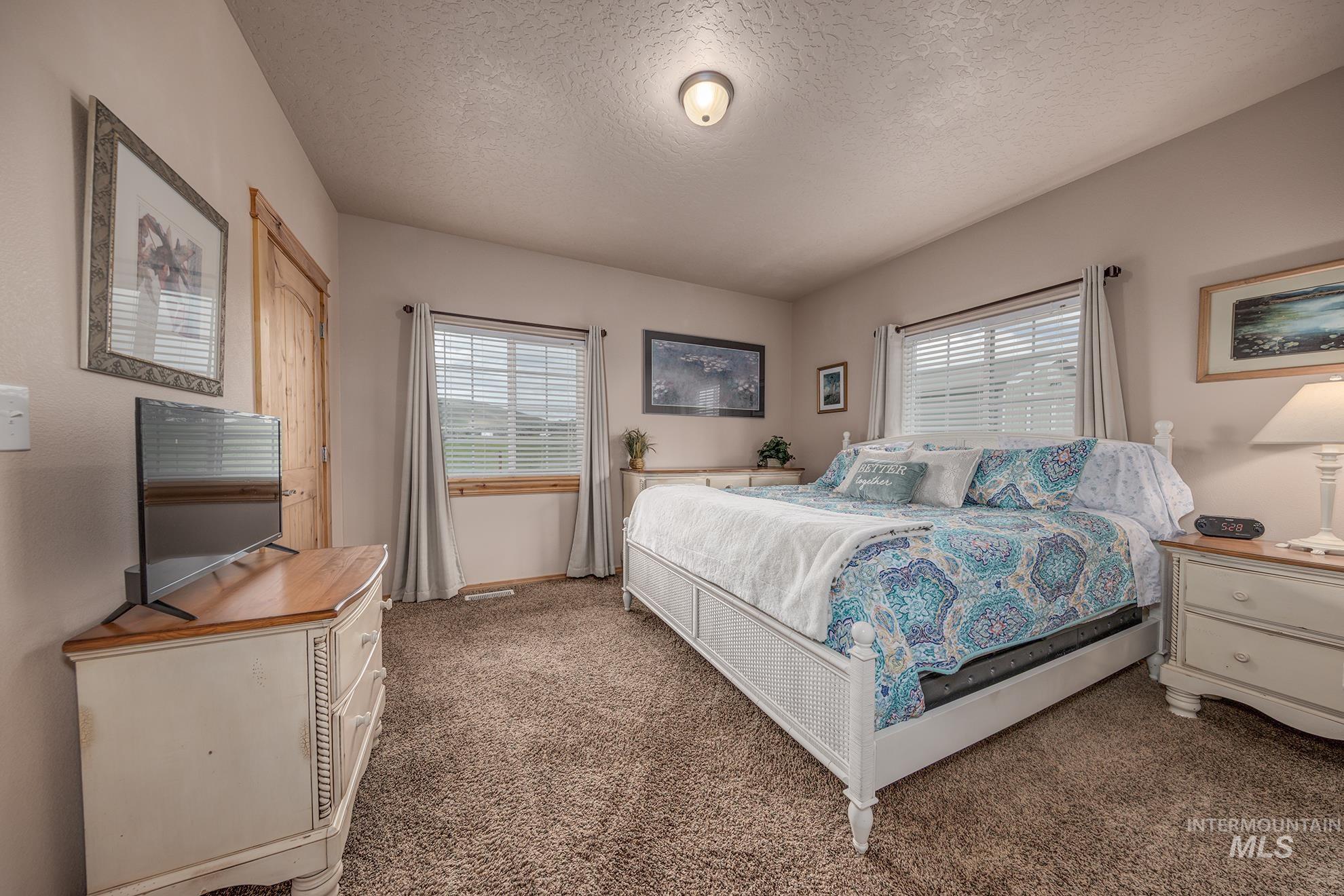 Guest house bedroom featuring multiple windows, a textured ceiling, and carpet