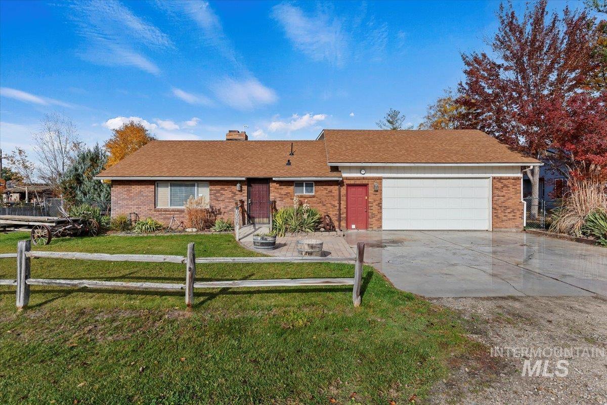 Ranch-style house with brick siding, a chimney, concrete driveway, roof with shingles, and an attached garage