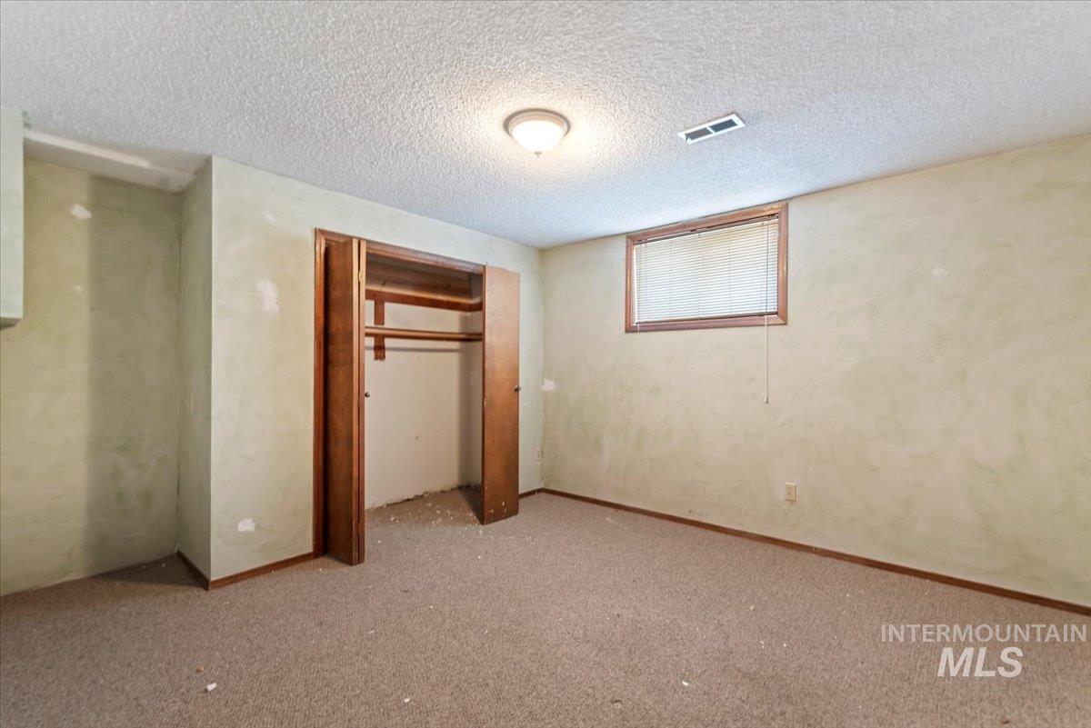 Unfurnished bedroom featuring a textured ceiling, a closet, and carpet flooring