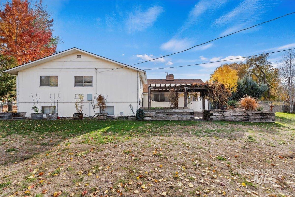 Back of property with a pergola, a chimney, and a lawn