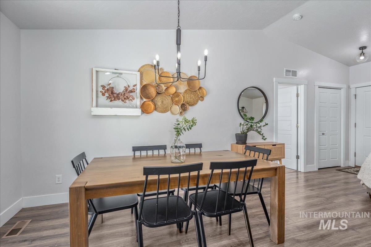 Dining room with a chandelier, wood finished floors, and lofted ceiling