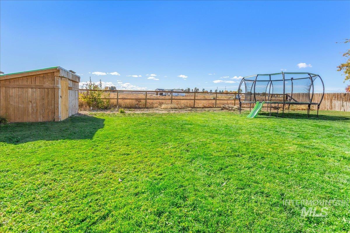 Fenced backyard featuring a trampoline