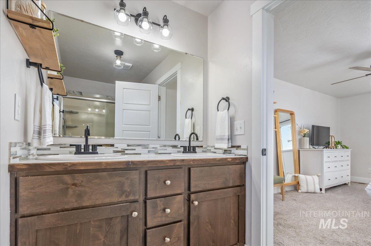 Bathroom featuring double vanity, a stall shower, light carpet, a textured ceiling, and a ceiling fan