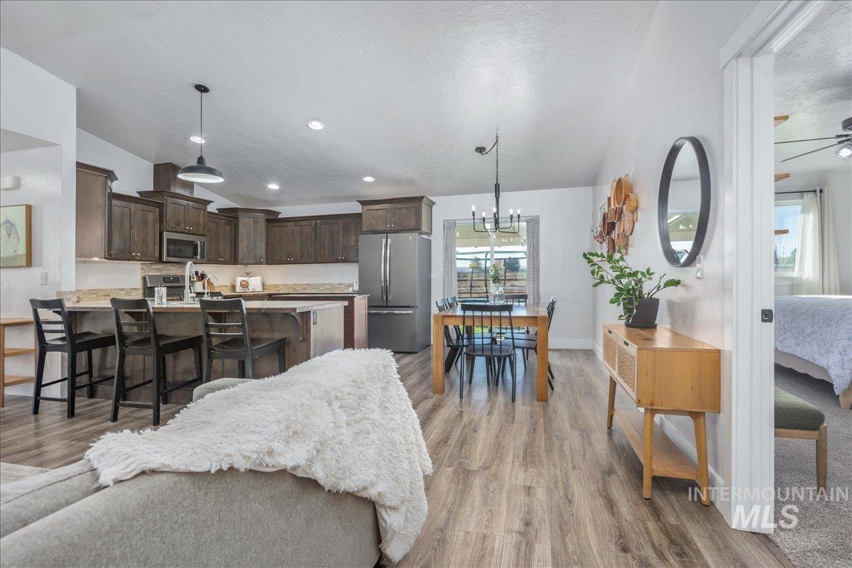 Living area with light wood-style flooring, a chandelier, lofted ceiling, a textured ceiling, and recessed lighting