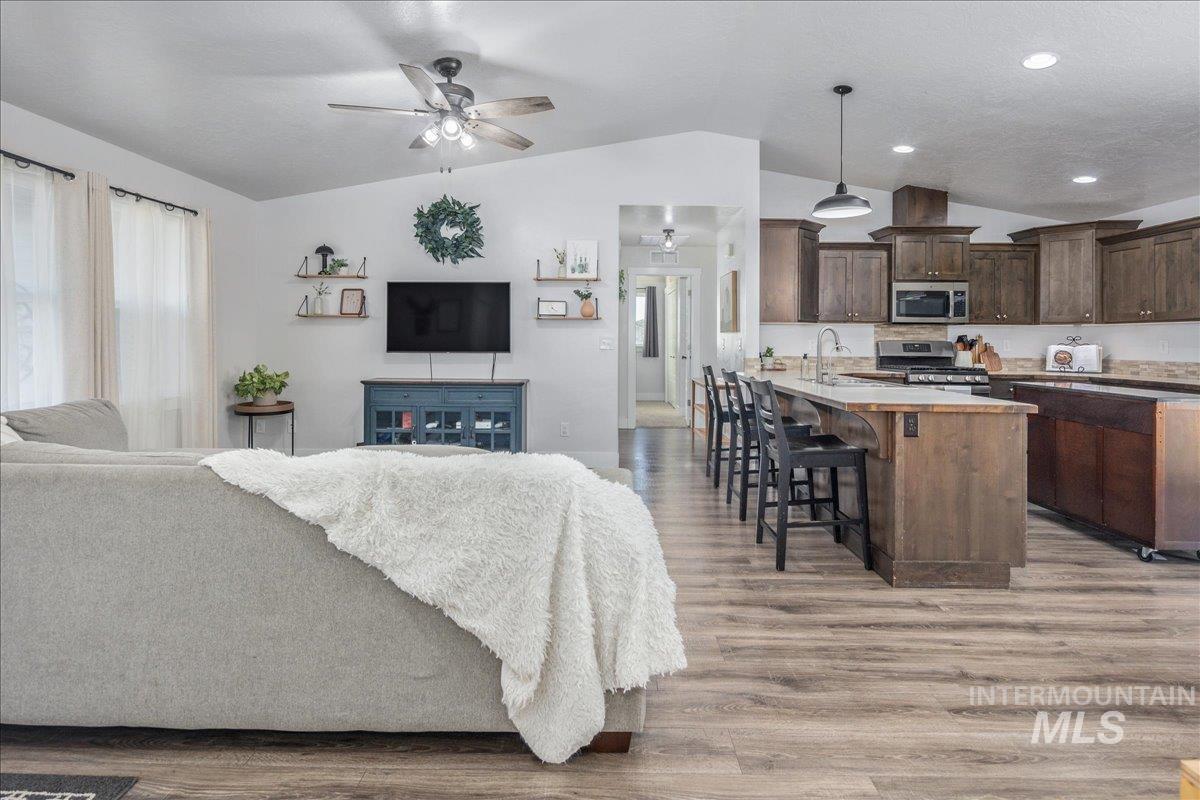 Kitchen featuring open floor plan, light countertops, lofted ceiling, a kitchen breakfast bar, and light wood-type flooring