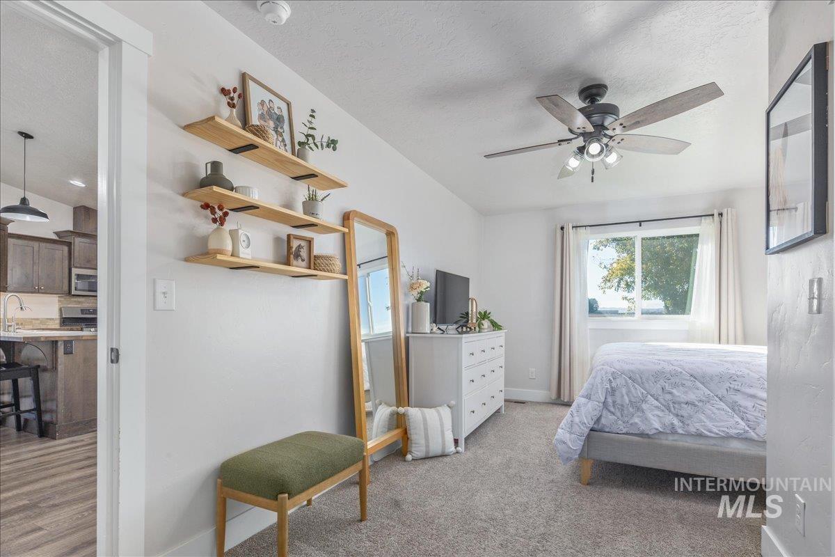 Bedroom featuring a ceiling fan, light carpet, and a textured ceiling