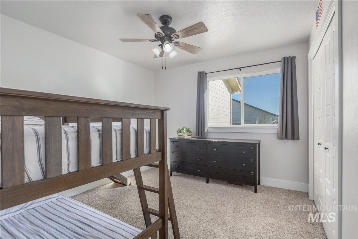 Bedroom with a closet, light colored carpet, and a ceiling fan