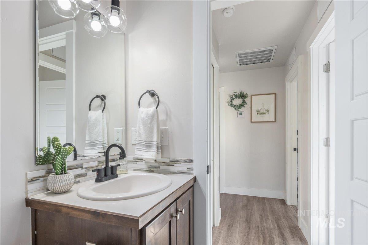 Bathroom featuring vanity, light wood-style flooring, a chandelier, and decorative backsplash