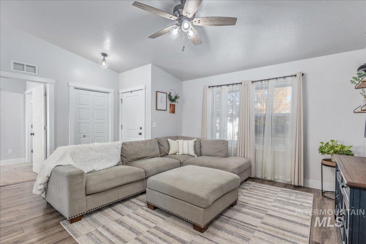 Living area with vaulted ceiling, wood finished floors, a ceiling fan, and a textured ceiling