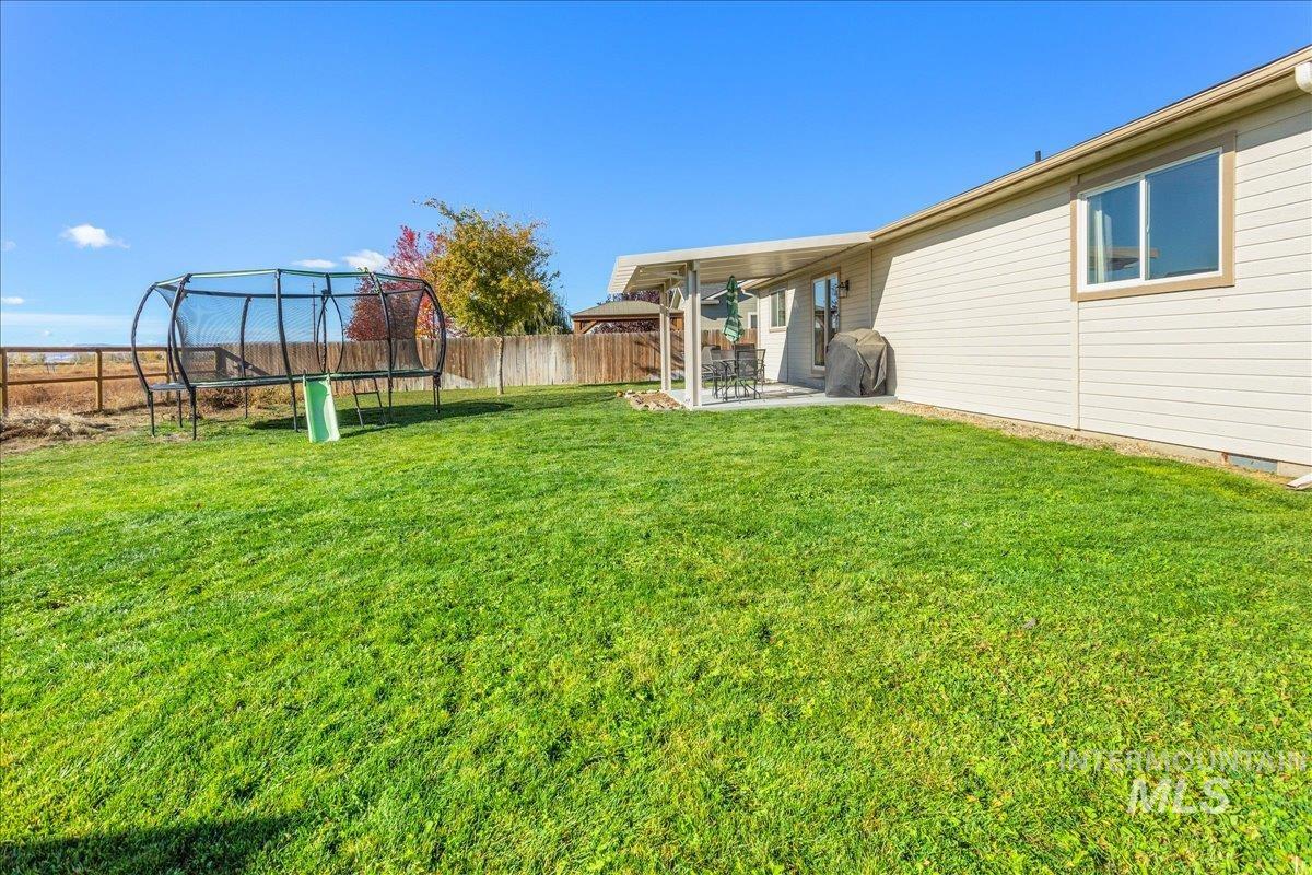 Fenced backyard featuring a trampoline and a patio