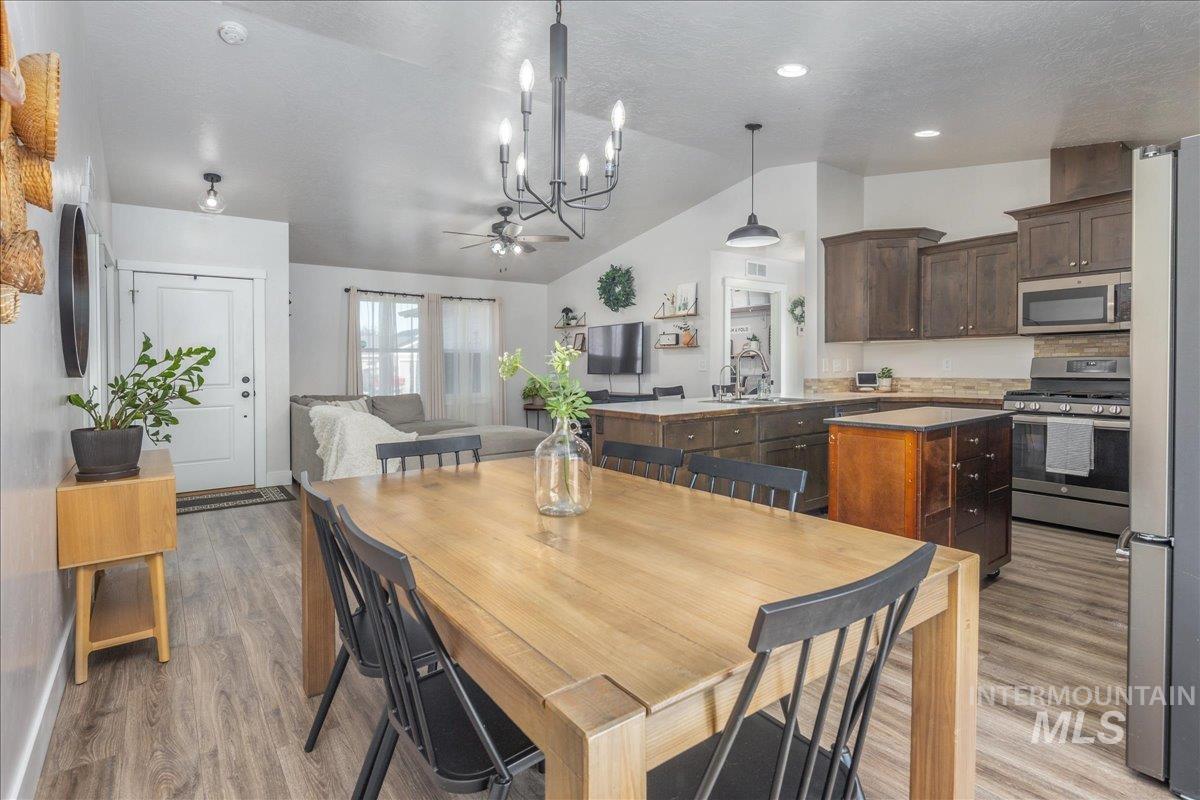 Dining room with a chandelier, lofted ceiling, light wood finished floors, and a textured ceiling