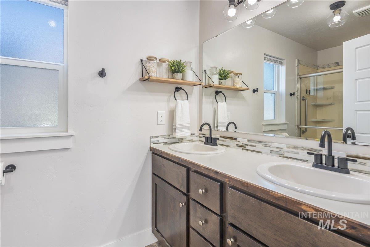Full bath featuring double vanity and a stall shower