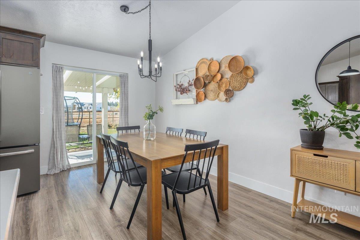 Dining area featuring light wood finished floors, vaulted ceiling, and a chandelier