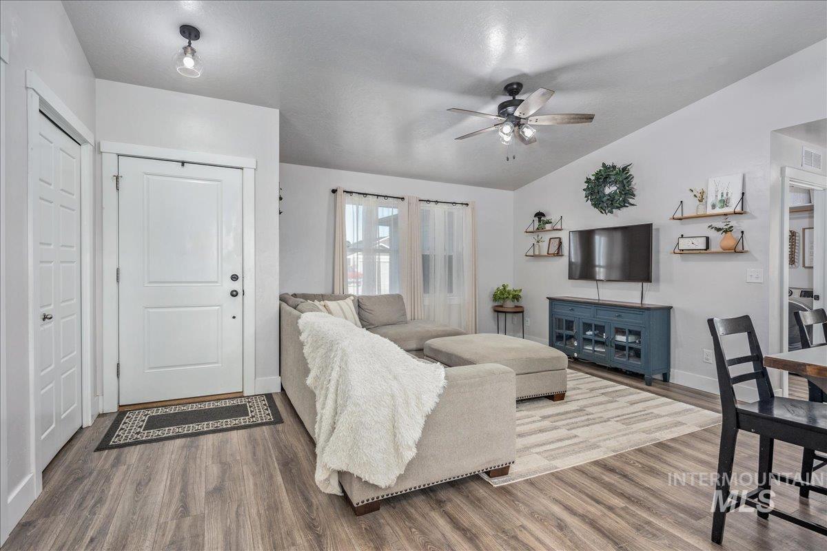 Living room featuring wood finished floors, ceiling fan, and vaulted ceiling
