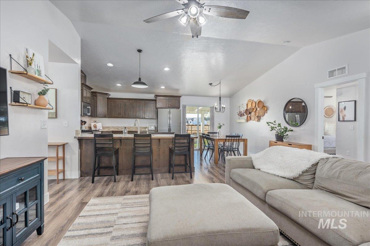 Living room featuring light wood-type flooring, recessed lighting, vaulted ceiling, ceiling fan, and a textured ceiling
