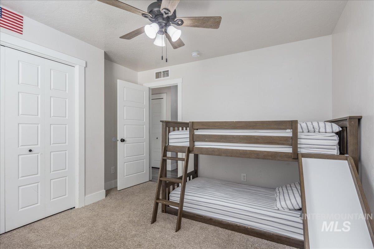 Bedroom featuring light colored carpet, ceiling fan, and a closet