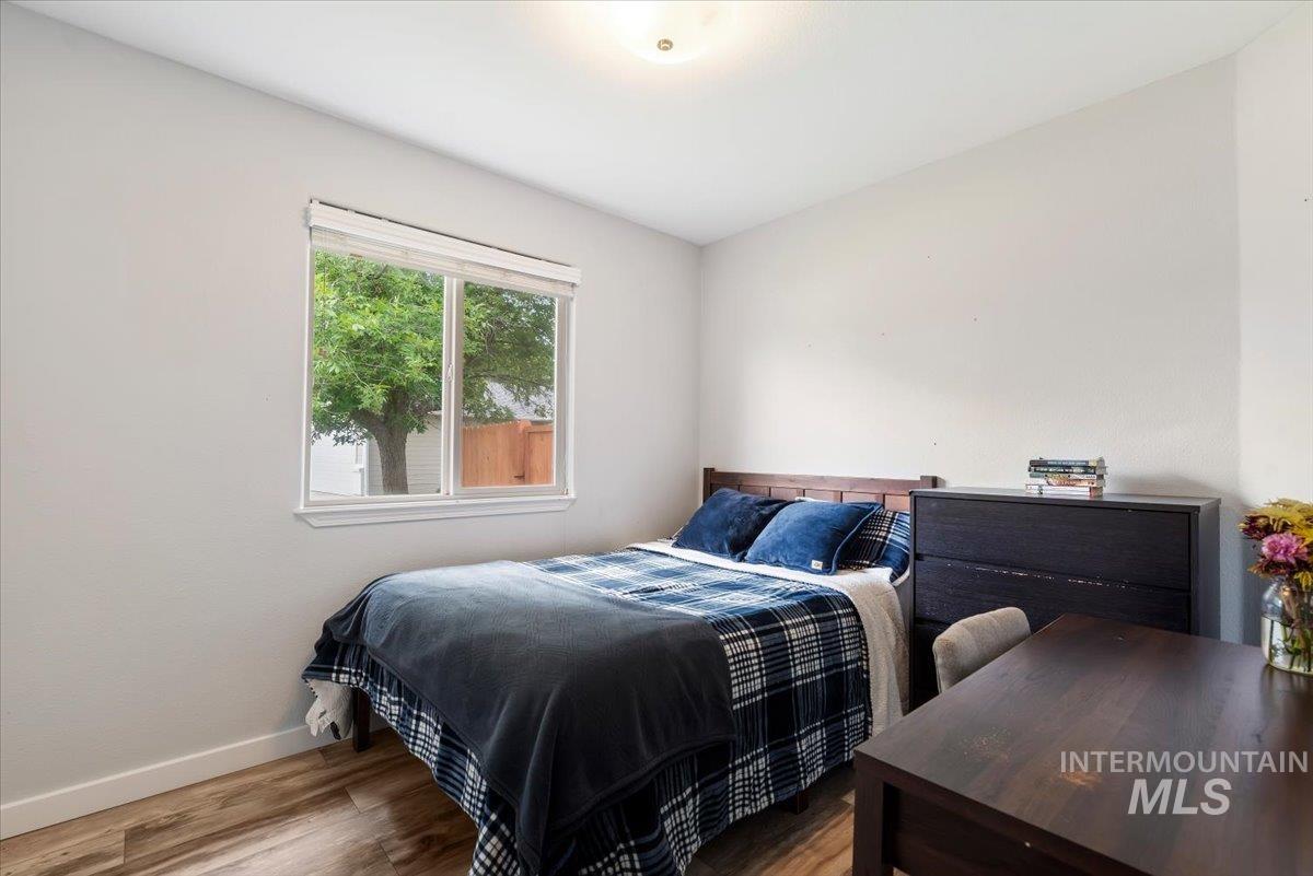 Bedroom featuring wood-finish flooring, a double window with white trim, and a ceiling-mounted light fixture