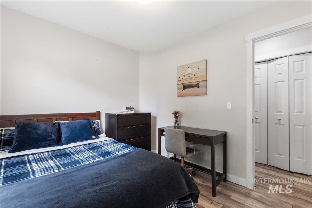 Bedroom featuring light-toned walls, wood-finish flooring, and a doorway with bi-fold closet doors
