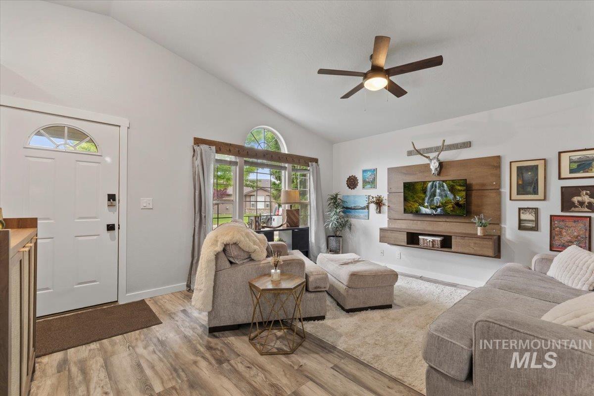 Vaulted ceiling living area featuring a wood-finish flooring, a contemporary ceiling fan, and a built-in media console