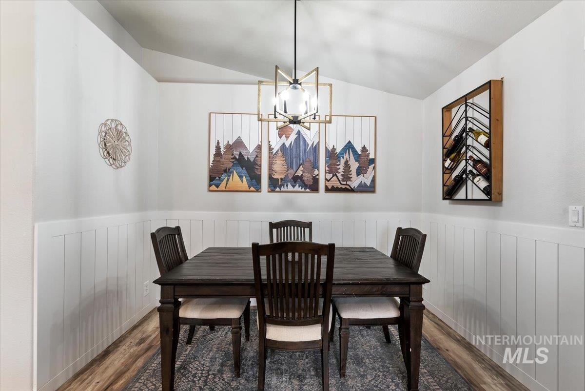 Dining area featuring wainscoting, wood-finish flooring, and a contemporary pendant light fixture