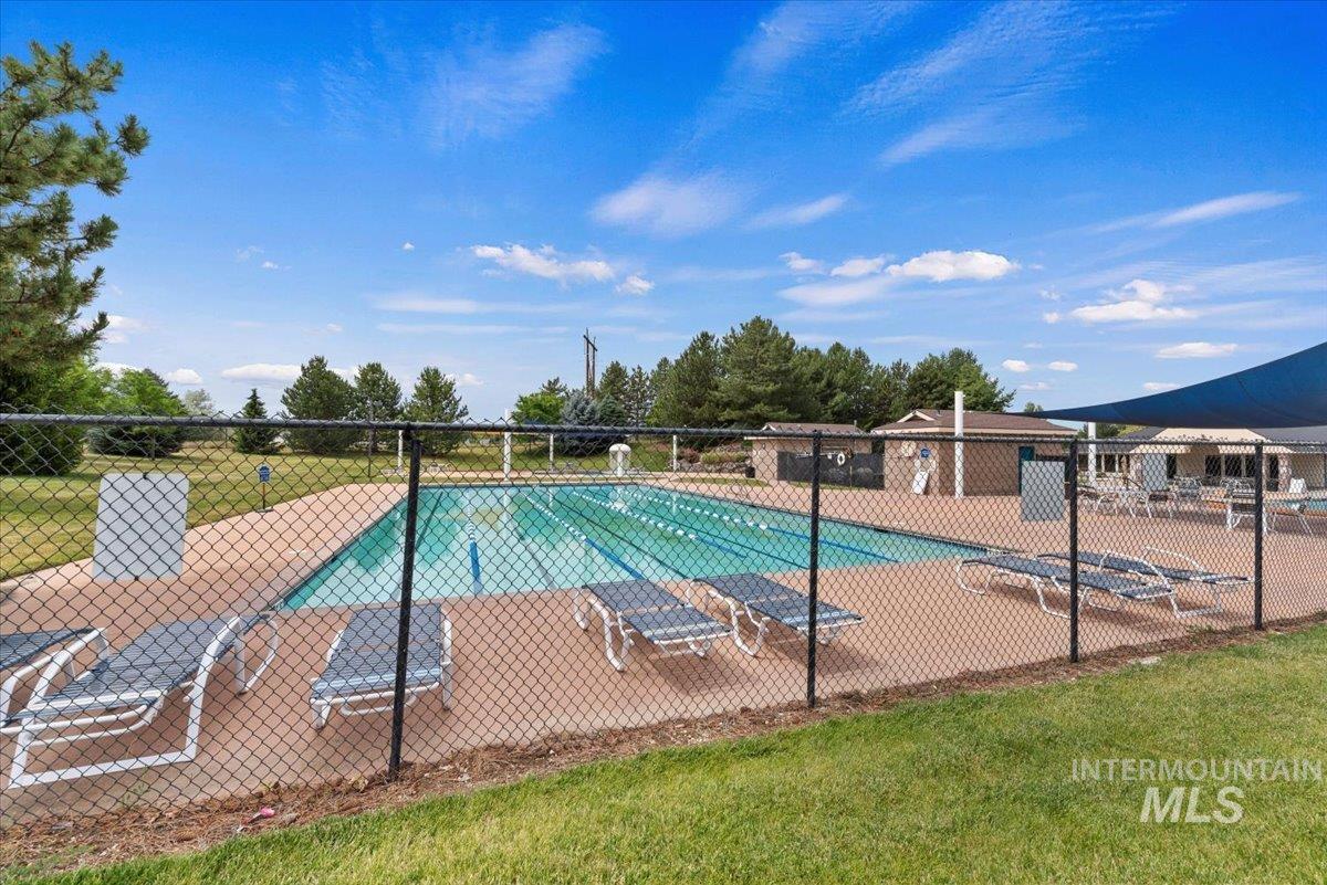 Outdoor swimming pool with integrated lap lanes, a surrounding concrete deck, and a shaded lounge area