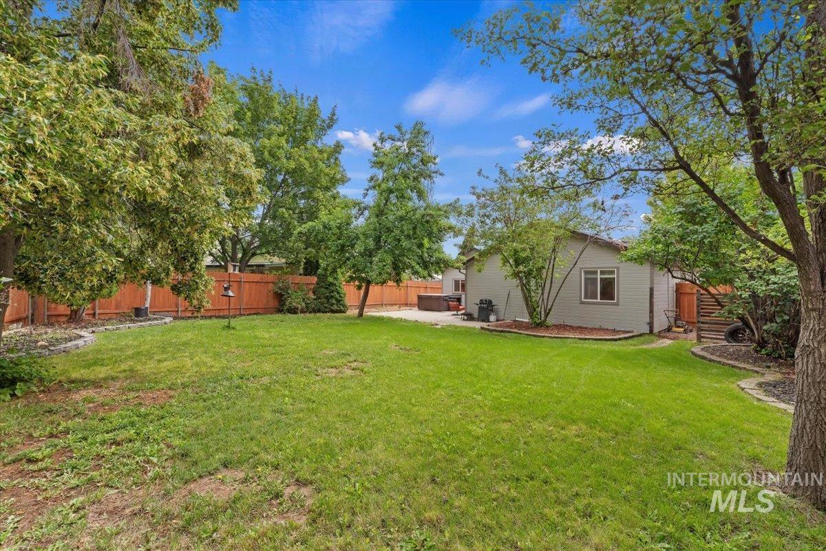 Expansive lawn area featuring mature trees and a wood privacy fence