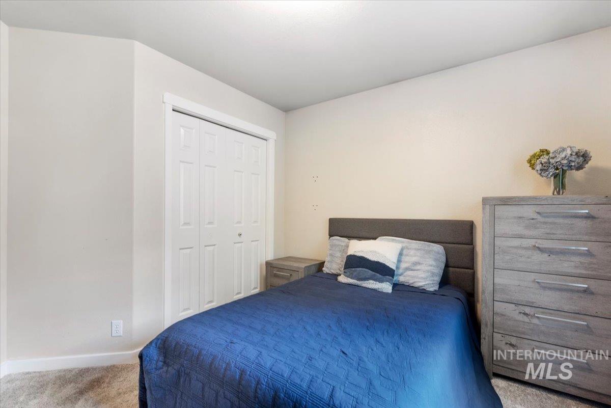 Room featuring soft neutral wall tones, textured carpeting, and a bi-fold closet door