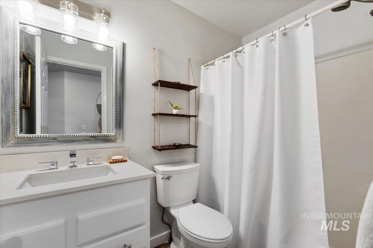 Bathroom featuring a single vanity with an undermount sink and polished chrome faucet, framed mirror, and a shower with a white curtain
