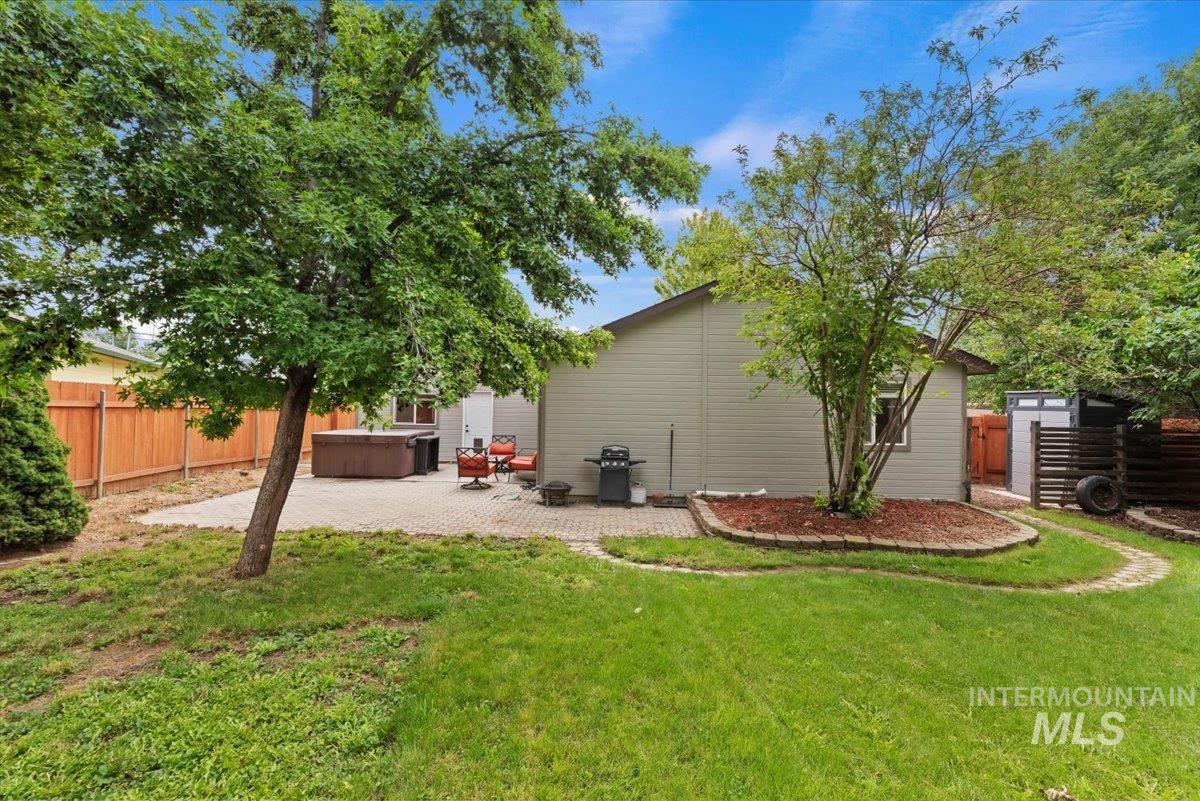 Expansive backyard featuring a paver patio area with a built-in hot tub