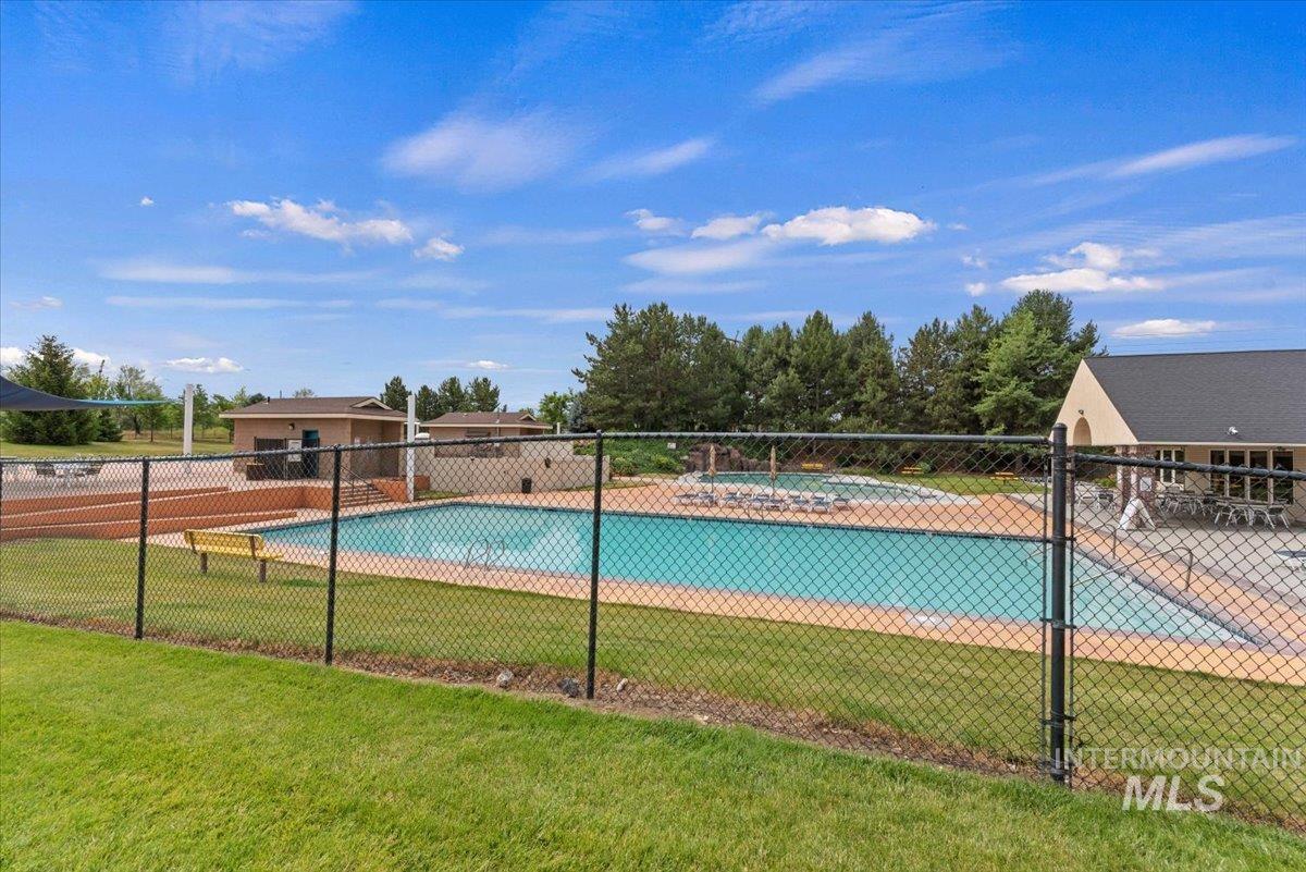 Community swimming pool with surrounding patio space and a nearby building