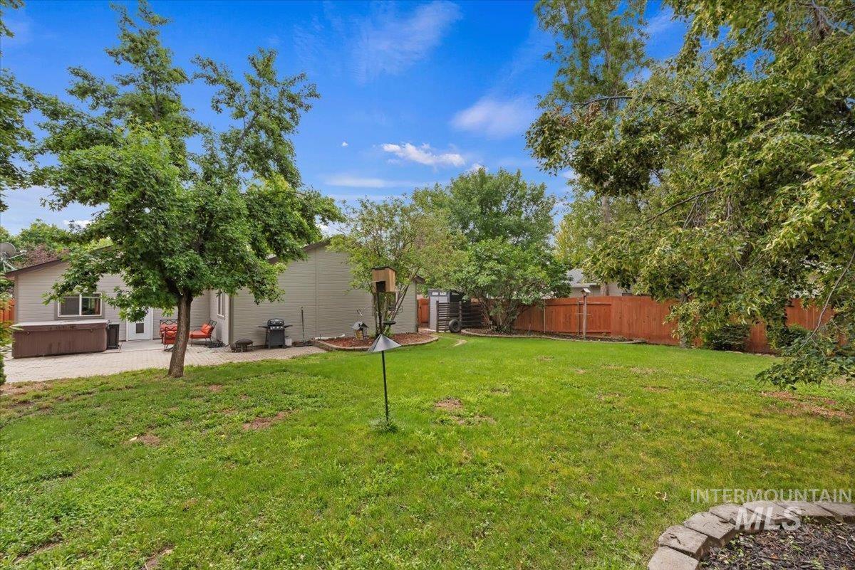 Expansive backyard featuring a manicured lawn, established trees, and a paver patio