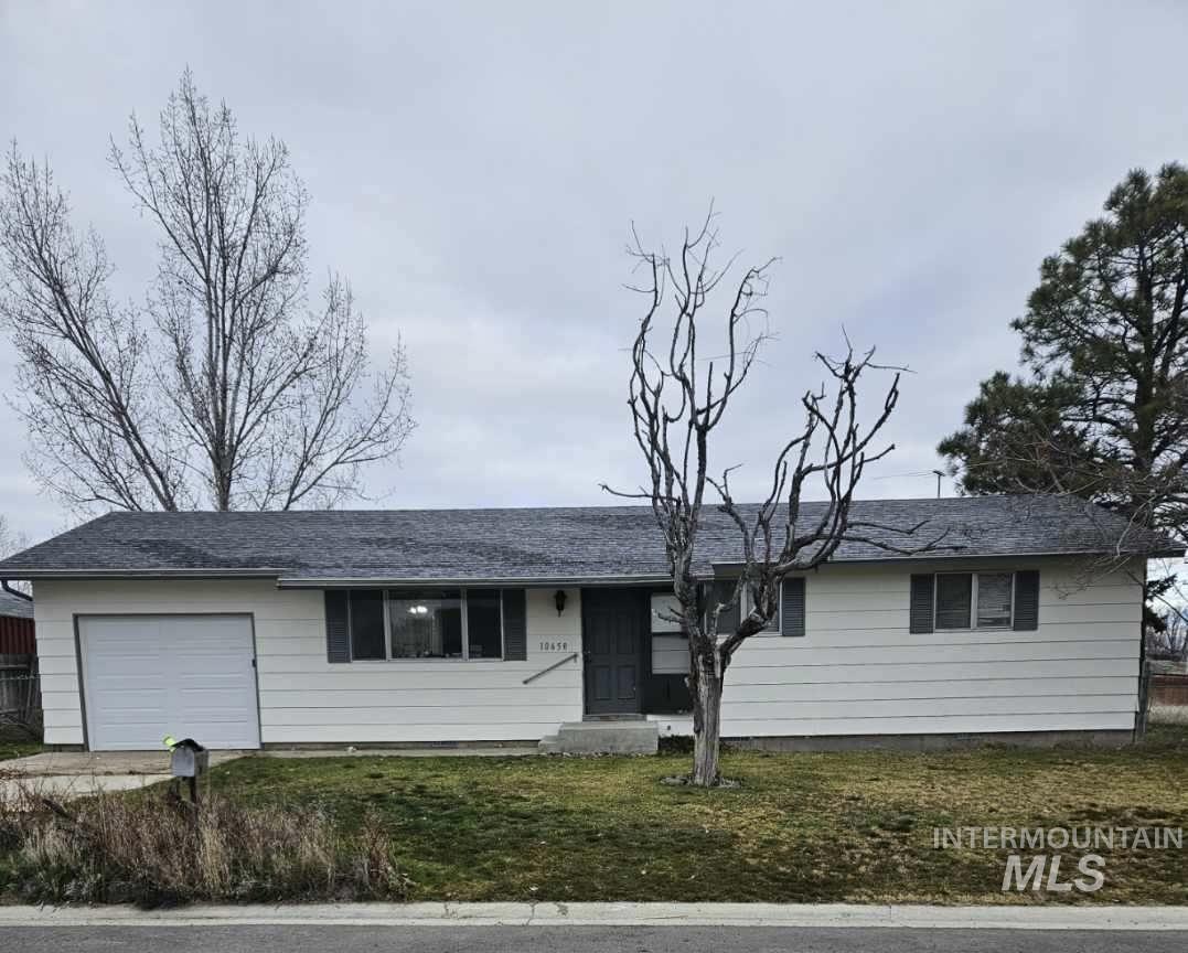 Single story home with an attached garage, a front lawn, roof with shingles, and driveway