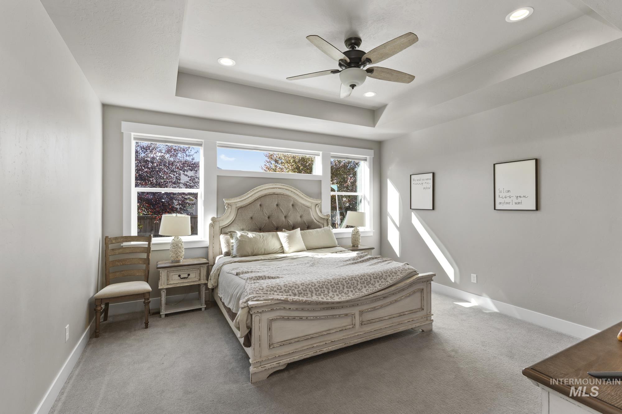 Bedroom featuring a raised ceiling, light colored carpet, ceiling fan, and recessed lighting